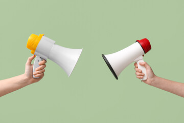 Female hands with megaphones on green background