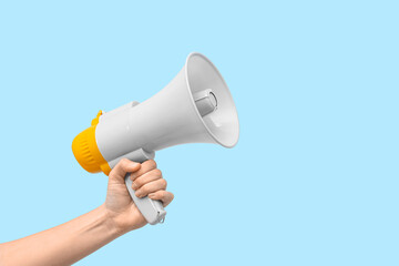 Female hand with megaphone on blue background