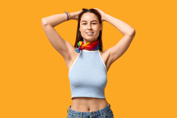 Beautiful young happy woman with piercing navel and LGBT flag on yellow background