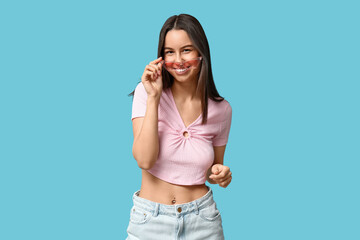 Beautiful young happy woman with piercing navel on blue background