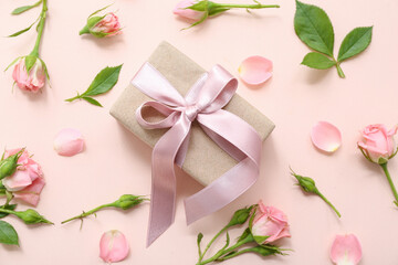 Beautiful wrapped gift box decorated with rose flowers on beige background