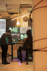 Team of people talking about getting illegal access into government database, working on cracking firewall encryption at night. Spies hacking computer system together, stealing data.