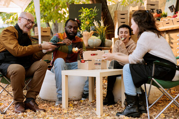 Young customers having good time with local vendors at farmers market, tasting variety of freshly harvested fruits and veggies. Happy clients and merchants eating homegrown healthy produce.