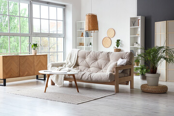 Interior of modern living room with soft sofa, shelving unit and coffee table