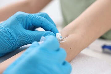 Nurse inputting catheter for IV drip in patient hand, closeup