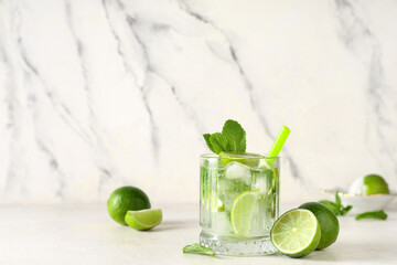 Glass of fresh Mojito cocktail with limes and mint on white background