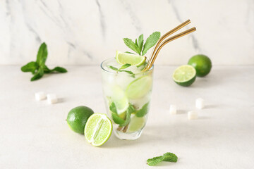 Glass of fresh Mojito cocktail with limes, mint and sugar on white background
