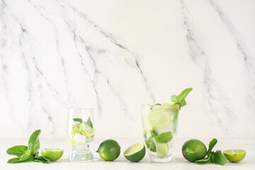 Glasses of fresh Mojito cocktail with limes and mint on white background