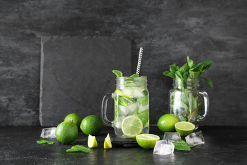 Mason jar of fresh Mojito cocktail with limes and mint on black background