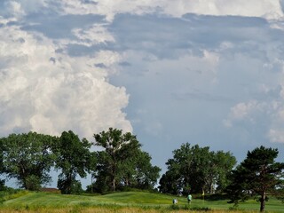 Golfers in the shadow of thunderstorms.