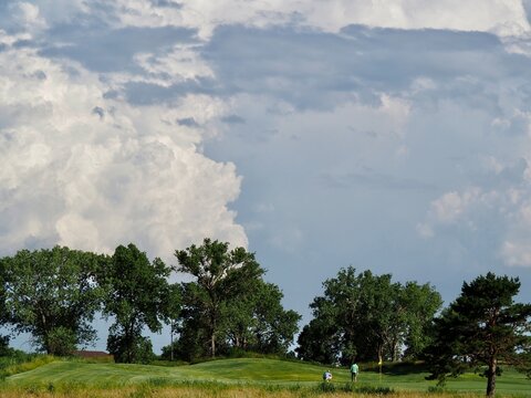 Golfers in the shadow of thunderstorms.