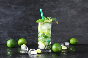 Glass of fresh Mojito cocktail with limes and mint on black background