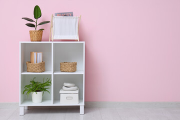 Interior of room with magazine holder, houseplant and shelving unit