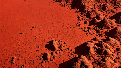 Aerial view of red rock formations in a desert landscape. Martian-like terrain with textured red sand and hills.