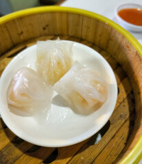 Shrimp dim sum served in a small white bowl. Food and drink photo concept.