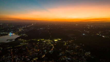 Fototapeta premium Curitiba in Paraná, Brazil. Aerial View. Wonderful sunset with views of buildings and Tanguá Park. Lake with reflection..