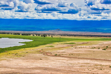 Endless vistas and bright blue skies over the great savanna plains and water bodies from the top of the Amboseli hill view point at Amboseli National Park, Kenya