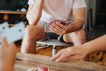 Friends enjoying their time together playing cards at home. A cozy and relaxed atmosphere.