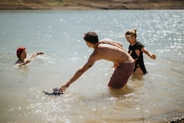 Group of friends having fun swimming in a clear lake on a sunny day, enjoying nature and making memories.