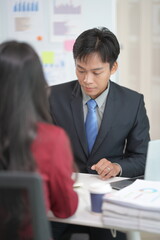 of Asian businessmen presenting investment cooperation, business data graphs in conference room, discussing investment projects and strategic planning with tablet computers in modern office