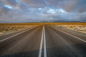 Vanishing point of an asphalt road in the middle of the Atacama desert during sunset