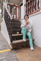 Woman sitting in outdoor antic stairs using phone alone