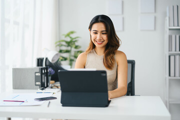 Confident Asian Business Woman Working on Tablet in Modern Office Setting with Bright Natural Light