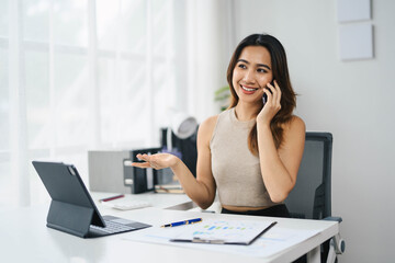 Confident Asian Business Woman Working on Tablet and Talking on Phone in Modern Office Environment