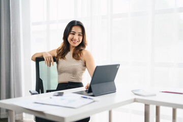 Confident Asian Business Woman Working on Tablet in Modern Office with Bright Natural Light