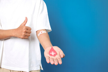 Man giving thumb up with the bandage plaster showing as a blood donation volunteer