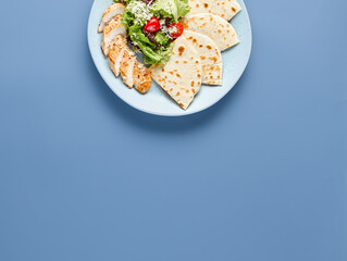 Fresh Chicken Caesar Salad with Tortilla on Blue Background - Healthy Meal Concept