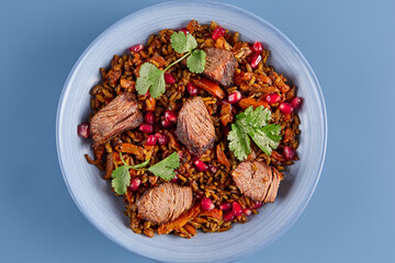Minimalist Beef and Pomegranate Pilaf on Blue Background