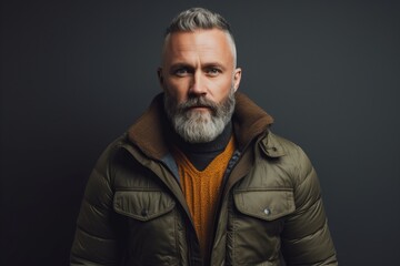 Obraz premium Portrait of a handsome middle-aged man with a gray beard in a warm jacket on a dark background