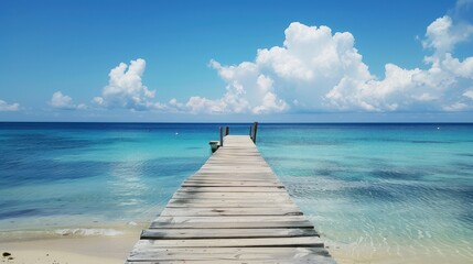 A wooden pier extending into the clear blue ocean under a bright sky, providing a serene and picturesque coastal scene.