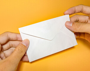 Plain white envelope held by woman's hand on yellow background, folded envelope mockup design...