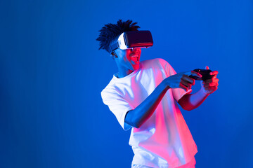 American African gaming player wearing VR controlling joystick hologram isolated blue pink neon...