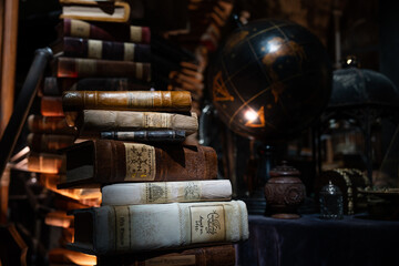 Naklejka premium JAPAN - Nov 13, 2023: Dimly lit antique study with a stack of old books a vintage globe and ornate artifacts on display in Hogwarts at Warner Bros. Studio Tour Tokyo, The Making of Harry Potter