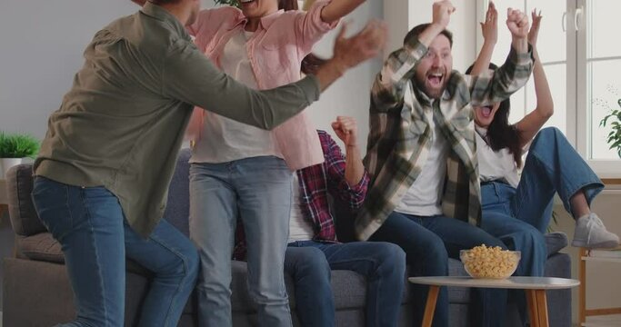 Football fans watching soccer on tv at home and celebrating happy victory, goal. Happy laughing smiling friends enjoy sport football match, overjoyed cheering for team winning, excited supporters