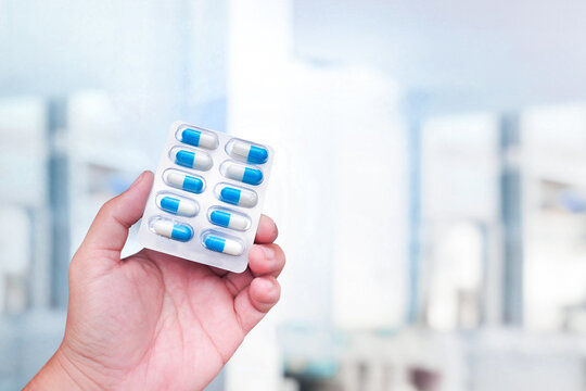 Amoxicillin capsules holding in a human hand , close up of antibiotic capsules pack , Medicine and medical concept