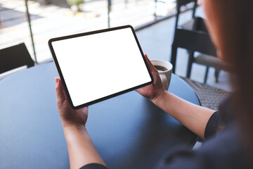 Mockup image of a woman holding digital tablet with blank white desktop screen in cafe