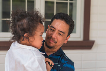 An Asian man in his 50s proudly bonding with his youngest son outdoors. The father is carrying his...