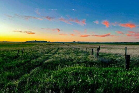 A rugged path forward into endless prairie under a pastel sunset