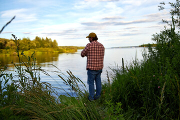 a fisherman in a plaid shirt fishing in the river in the evening