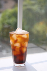 a glass of iced coffee on a white table