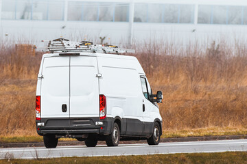 Commercial work van driving with tools and ladder on the road