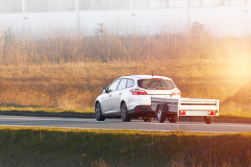 Car hauling trailer on sunny rural path