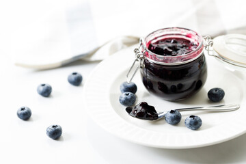 Blueberry jam with fresh berries on white marble table background. Selective focus.