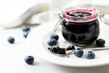 Blueberry jam with fresh berries on white marble table background. Selective focus.