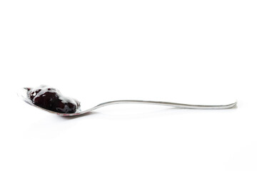 Spoon of blueberry jam on white marble table background. Selective focus.