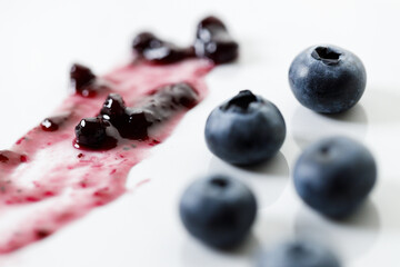 Blueberry jam with fresh berries on white marble table background. Selective focus.